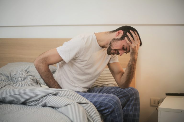 Man dealing with pain while sitting in bed